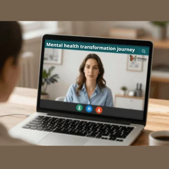 A person in the foreground, viewed from behind, observes the screen of a laptop displaying a video call. Appearing on the screen is a young woman with brown hair and a blue shirt, situated in a brightly lit office environment. Prominently displayed at the top of the screen is a dark green banner featuring the text "Mental health transformation journey" and the "Vicney" logo: an orange butterfly.